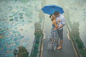 Pareja besos debajo el lluvia en su primero fecha foto