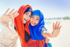 dos musulmán muchachas sonriente a cámara foto