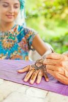 de cerca Disparo de un mano dibujo alheña tatuaje en un mujer manos. suave enfocar. foto