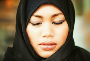 serious muslim indonesian woman with closed eyes photo