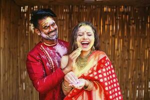 Beautiful Indian couple in ethnic dresses playing Holi and putting colors on the face photo