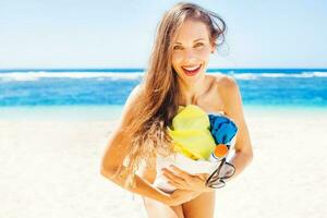 laughing woman holding a beach bag on a beach in bali photo