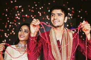 Indian couple decorating their house with the electric lights for Diwali  celebration photo