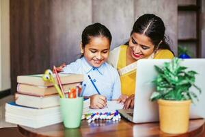 indio niña consiguiendo entrenamiento en su estudios, aprendizaje a hogar con su hembra profesor foto