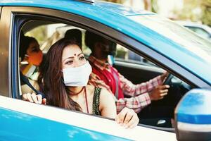 Happy Indian family wearing Coronavirus protective face masks traveling in a car together photo