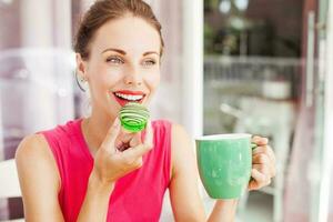 woman looking at macaron she's going to eat. Lovely color combination of pink and green photo