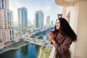 woman dringking tea in a luxury apartment with the cityscape view in dubai, UAE photo