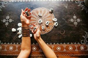 hands holding runes stones on an ornate table photo