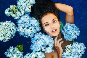 dramatic portrait of a woman floating an a swimming pool full of flowers photo