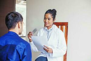 Young female Indian doctor consulting a patient while holding medical reports and prescription medicines in her hands photo