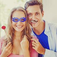 Amateur style portrait. Couple posing with stick lips, mask, mustache accessories. photo