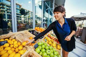 young caucasian woman picking lemons from an open market shop photo