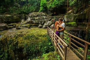 beautiful couple standing and kissing on a bridge photo