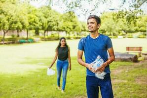 Indian man and woman collecting plastic waste in the park, working as volunteers photo