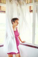 Pregnant woman near the window at home photo