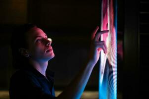Man clicking on a futuristic screen at night photo