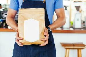 Package design template mockup. Man holding blank coffee package photo