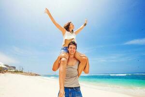 hermosa caucásico Pareja. hombre lleva mujer a cuestas en un playa foto