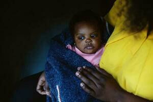 Cute serious african american baby in mother's hands photo