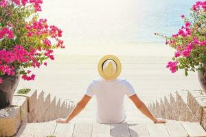 Faceless portrait from the back of a man in a hat sitting on the beach in Dubai photo