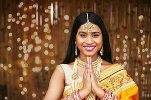 hermosa indio mujer en sari mirando a cámara y haciendo namaste gesto, saludo huéspedes, sonriente foto