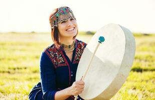 mujer en tradicional étnico ropa jugando tambor foto