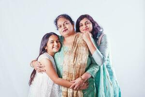 Female generations Indian grandmother, mother and daughter posing together over studio white background photo