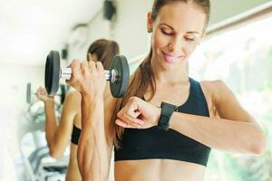 Smart watch showing a heart rate of excercising woman in gym photo