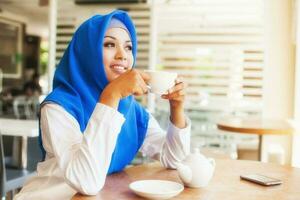 asian muslim woman enjoying a cup of tea photo