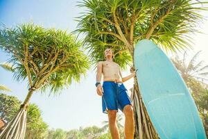 guy standing surfboard happy shore tree photo