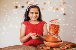 Beautiful Indian little girl doing puja with kalasha on Navratri days, holding diya photo
