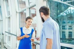 Beautiful young flight attendant checking documents of male tourist photo