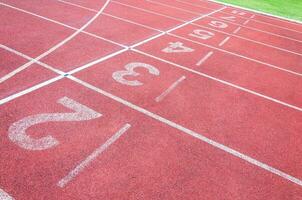 números comenzando punto en rojo corriendo pista, correr pista y verde hierba, directa atletismo corriendo pista a deporte estadio foto