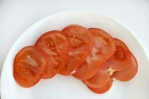 Chopped tomato on a white plate. Tomato salad. Sliced vegetables. Red tomatoes. photo