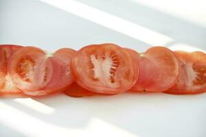 Chopped tomato on a white plate. Tomato salad. Sliced vegetables. Red tomatoes. photo