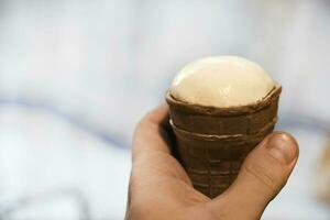 An ice cream cone in the young man's hand. Delicious ice cream in your hand. photo