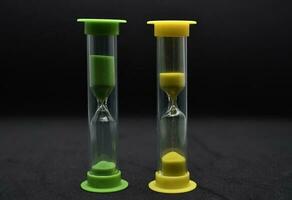 Multicolored glass hourglass on a black background. Vintage hourglass. photo