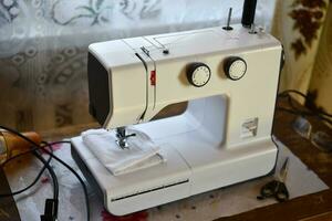 un blanco de coser máquina en el habitación. Procesando de ropa con un de coser máquina. foto