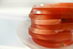 Chopped tomato on a white plate. Tomato salad. Sliced vegetables. Red tomatoes. photo