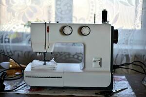 A white sewing machine in the room. Processing of clothes with a sewing machine. photo