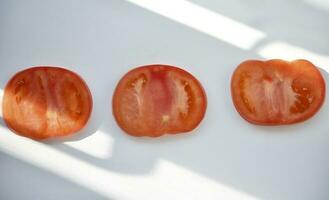 Pieces of red tomato on a white background. Chopped tomatoes. photo