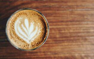 A cup of hot coffee with latte art on the wooden table. photo