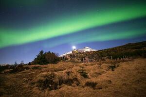 The beautiful Aurora trails over the snowcap mountain in the countryside of Iceland. photo