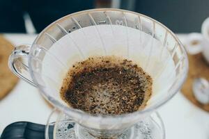 Close up of coffee drip filter after Barista pouring hot water on ground coffee. photo