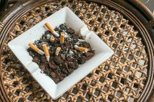 Ashtray and smoke cigarettes on wooden table. photo