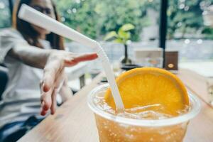 Close up of the Orange juice with women try to catch it on the background. photo