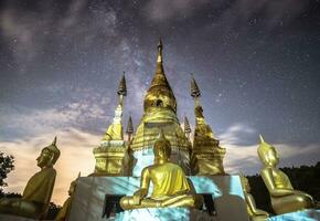 The milky way over the Buddhist pagoda in Chiang Rai province of Thailand with beautiful starry night. photo