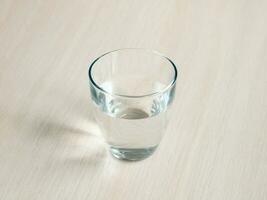 Glass of mineral water on wood table. Close up the purified fresh drink water from the bottle on table. photo