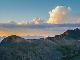 rocoso montaña en amanecer nublado cielo. atmosférico mínimo montaña paisaje con lila amanecer cielo. escénico minimalista paisaje con púrpura puesta de sol en montañas. siluetas de montañas en antecedentes. foto