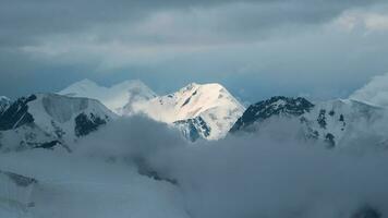 Wonderful minimalist panoramic landscape with big snowy mountain peaks above low clouds. Atmospheric minimalism with large snow mountain tops in cloudy sky. photo